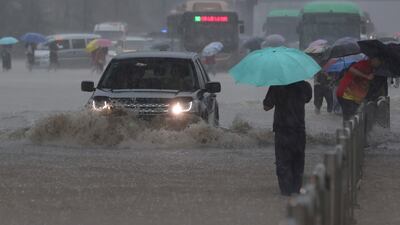 Traffic struggles through flooding in Zhengzhou, the capital of China's central Henan province. The banks of rivers are reported to have burst, leaving people in waist-high water.