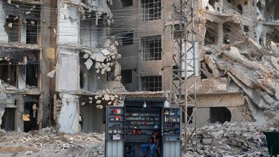 A man waits for customers at a stall beside war-damaged buildings ahead of a parliamentary election in the Damascus suburb of Daraya, Syria. AP