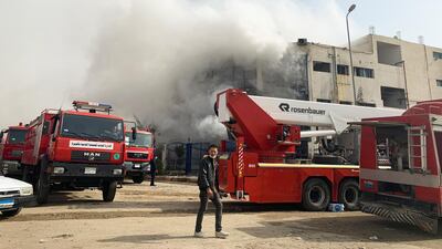 A man looks on near firefighting trucks at the scene after a fire broke out in a garment factory north of Cairo, Egypt. Reuters