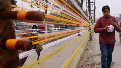 An Indian worker prepares balls of coloured kite thread on a roadside in Amritsar on January 8, 2014. Narinder Nanu/AFP