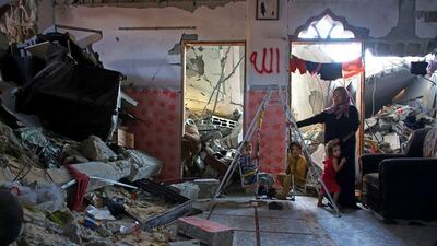 Palestinian woman Badiya Hasani with her children by a swing set inside the home they continued to live in despite it being heavily damaged in the Sha’af neighbourhood of Gaza.