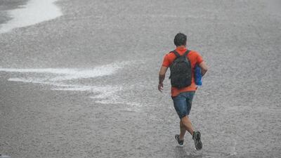 A pedestrian is caught in the open in London during the downpour. The Met Office issued yellow thunderstorm warning forecasts for parts of England and Wales. PA