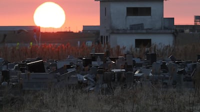 The sun rises past a cemetery and abandoned building in Namie, Fukushima prefecture, Japan on the seventh anniversary of the Great East Japan earthquake on March 11, 2018. Jiji Press / AFP