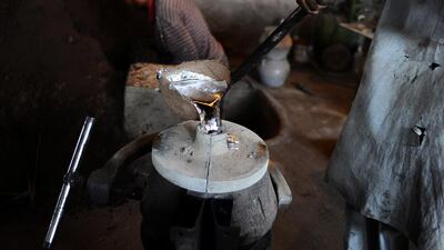 A labourer pours molten aluminium into a mold at a workshop in Herat.
