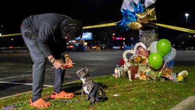 Cameron Bertrand with the gun violence activist group Violence Intervention and Prevention talks to his dog at a memorial for those killed. Getty Images / AFP