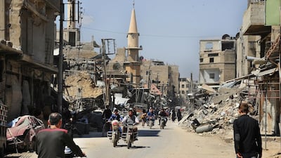 People walk travel down a bombed street in Douma on April 14, 2018 after Syrian police units entered the town in Eastern Ghouta where international inspectors are due to visit to investigate an alleged chemical weapons attack. Sana via AP
