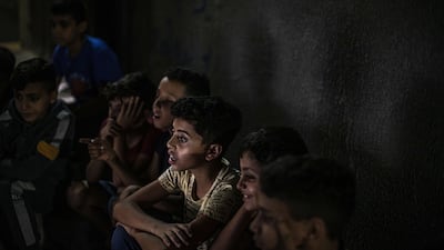 GAZA CITY, GAZA - NOVEMBER 7: Palestinian children attend a movie screening in the street in Jabalia refugee camp on November 7 2021 in Gaza City, Gaza. Gaza's first cinema was built in 1944 and by the 1960s there were as many as 10 operating, however political disputes, conflict, and religious reasons caused the closure of all cinemas during the first Palestinian intifada in 1987 and they continued to remain closed due to government and religious restrictions. The last show in a cinema was screened 24 years ago. Today, traces of only three of the old cinemas remain, Al-Nasr Cinema and Amer Cinema are still standing, although heavily damaged and abandoned and the third, Al-Samer Cinema has been turned into a car licensing facility. Recently, a fully equipped mobile cinema bus was established and has once again given Gaza residents a chance to experience the feeling of watching a film at the cinema, an event many have never experienced in their lives. The shuttering of cinemas forced many residents to seek out other ways of viewing and screening films, makeshift street cinemas, home projectors and cafe film screenings are all ways people have found to take in a film, with the opening of the new cinema bus, which can accommodate up to 50 passengers and creates the real experience of stepping into a cinema hall, it brings an opportunity for residents of all ages to once again be immersed in the cinema experience, bringing hope and a reprieve from the struggles of daily life in Gaza. (Photo by Fatima Shbair/Getty Images)