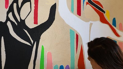 Amrita Sethi working on one of her murals 'Halla Walla', which shows a high-five greeting between an Emirati man and woman
