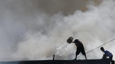 Filipinos throw buckets of water on a fire at a residential area in Quezon City, east of Manila. Rolex Dela Pena / EPA