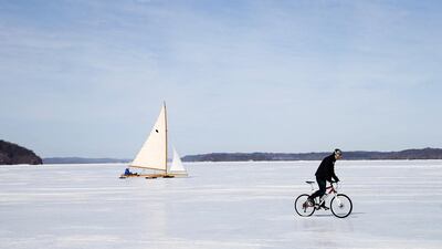 An antique ice boat sails behind a cyclist across the frozen Hudson river. (Mike Segar / Reuters / March 7, 2014)