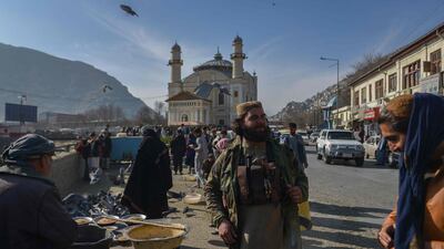 A member of the Taliban stands next to an Afghan hawker selling bird feed at a market area in Kabul. Photo: AFP