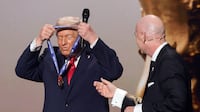 US President Donald Trump puts on his medal as he is awarded the peace prize by Fifa president Gianni Infantino. Reuters