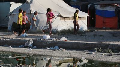 Palestinian children walk between tents used as temporary shelter and stagnant wastewater in Deir Al Balah in central Gaza. AFP