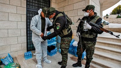 A member of the Palestinian security forces is assisted into a protective suit before delivering food supplies to a hotel under quarantine. AFP