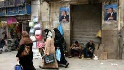 Algerians walk past a campaign poster promoting the president, Abdelaziz Bouteflika, who is standing for re-election. Algerians disillusioned by high unemployment and ossified politics are widely expected to boycott tomorrow's vote.