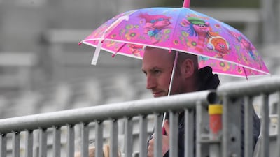 A fan shelters from the rain at Malahide. Clodagh Kilcoyne / Reuters