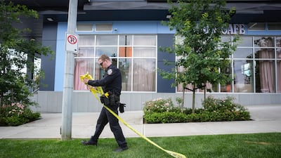 A police officer with crime scene tape outside Kap's Cafe in Surrey, British Columbia, Canada. AP