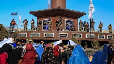 Taliban stand guard as women carry placards during a rally in Kabul demanding the US and international community unfreeze Afghanistan's assets. EPA