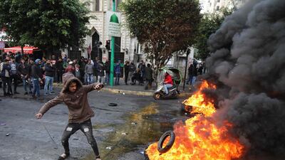 A protester throws a tyre on a burning pile blocking the road in the capital Beirut. AFP