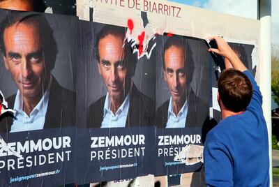 A man tears off posters showing far-right talk show host Eric Zemmour, who has not formally entered the race for president. AP