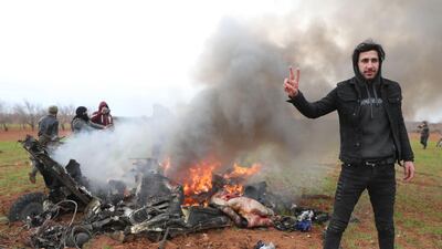 Syrian rebel fighters gather around the burning remains of a military helicopter after it was shot down over the village of Qaminas, about 6 kilometres southeast of Idlib city in northwestern Syria on February 11, 2020. AFP