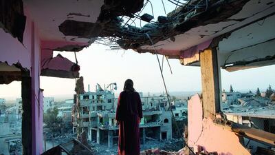 Hidya Atash stands on the top floor of what remains of her home in the Shujayea neighbourhood of Gaza City on August 8. The building was hit two weeks earlier by a warning rocket from Israel, causing the family of 40 to flee. Heidi Levine for The National