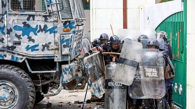 Riot police shelter behind a security vehicle as demonstrators throw stones. AFP
