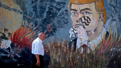 A Palestinian man walks past a mural depicting US President Donald Trump with a footprint on his face, on a street in the occupied Gaza City. AFP