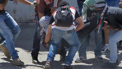 Masked Palestinian youths carry Nadim Nawara after he was shot by Israeli forces outside the Israeli-run Ofer prison, on May 15, 2014. Nawara later died from his injuries. Abbas Momani/AFP Photo