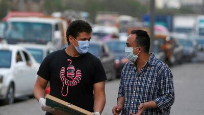 Men wearing face masks walk along a street before curfew in Shubra El Kheima, Al Qalyubia Governorate, north of Cairo, Egypt. Reuters