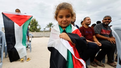 A girl holds a Palestinian flag in the central Gaza Strip on Thursday after US President Donald Trump announced that Israel and Hamas agreed on the first phase of a Gaza ceasefire. Reuters