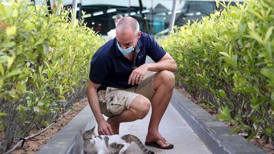 Sean Steyn, a resident of Al Bandar, plays with Honey, a stray cat that lives on the site of the development at Al Raha Beach. Khushnum Bhandari / The National