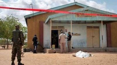 Members of the Kenyan security forces inspect the scene, as a body lies covered by a sheet, outside the African Inland Church in Garissa, Kenya.