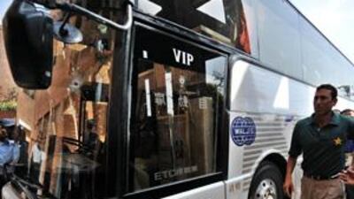The Pakistan captain Younus Khan, right, walks past a bullet-ridden bus which was carrying the Sri Lanka cricket team and attacked outside the Gaddafi Stadium.