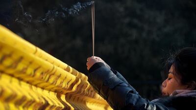 A woman prays for health and fortune on the first day of the New Year at Yonghegong Lama Temple in Beijing. AP Photo