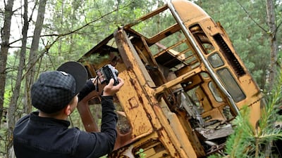 A visitor takes a picture at a wreckage of a bus in the ghost city of Pripyat during a tour in the Chernobyl exclusion zone. Courtesy AFP