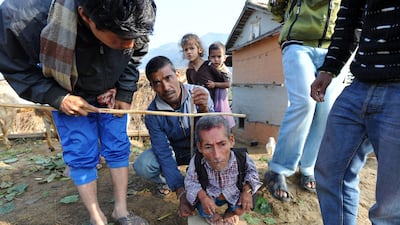 Chandra Bahadur Dangi, a 72-year-old Nepali who claims to be the world's shortest man at 56 centimetres (22 inches) in height, looks on as villagers measures him near his home in Reemkholi village, Dang district, some 540 kilometres southwest of Kathmandu???