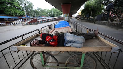 Homeless men sleep on a handcart parked on a road divider in a containment zone during lockdown in Bengaluru, India. AP Photo