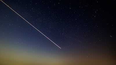 A long-exposure image shows an aircraft flying in the sky prior to the Perseids meteor shower at Al Khatim Desert in Abu Dhabi. Photo: EPA