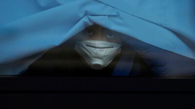 A passenger who disembarked from the quarantined Diamond Princess cruise ship peeks out of a bus window. AP