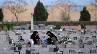 An Iranian couple sit in a cemetery where Covid-19 victims are buried, south of Tehran. Reuters.
