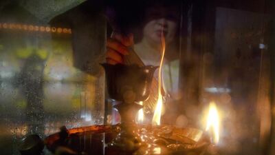 A woman burns incense at a makeshift altar.
