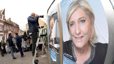 Photographers and journalists stand next to a campaign poster of French presidential election candidate for the far-right Front National party Marine Le Pen outside a polling station in Henin-Beaumont, northern France. Francois Lo Presti/AFP