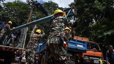 Technicians lift water pumps to the drilling site near Tham Luang cave. Lillian Suwanrumpha / AFP