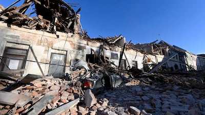 This photograph taken on December 29, 2020, shows the wreckage of a car and damaged buildings in Petrinja, some 50kms from Zagreb, after the town was hit by an earthquake of the magnitude of 6.4. The tremor, one of the strongest to rock Croatia in recent years, collapsed rooftops in Petrinja, home to some 20,000 people, and left the streets strewn with bricks and other debris. Rescue workers and the army were deployed to search for trapped residents, with no casualties initially reported. / AFP / DENIS LOVROVIC