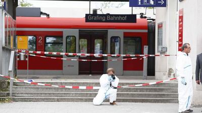 A police officer takes pictures at the train station in Grafing, Germany. A man attacked passengers with a knife at a train station in the Munich area in southern Germany early on Tuesday, leaving four people with life-threatening injuries. Michaela Rehle / Reuters