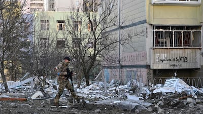 A member of Ukraine's defence forces walks by a damaged apartment block in Kyiv. AFP