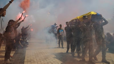 Ukrainians burn flares during a farewell ceremony in Kyiv for servicemen killed on duty in 2025. EPA