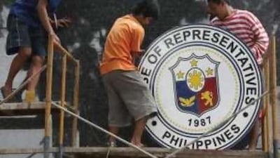 Filipino workers put up the logo of the House of Representatives. The Philippine president, Benigno Aquino, is expected to criticise his predecessor, Gloria Macapagal Arroyo, in a joint session in front of both houses.