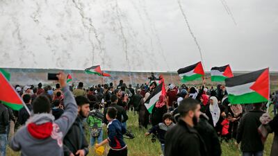 Palestinians flee as Israeli tear gas grenades begin to drop on a demonstration near the Gaza Strip's border with Israel on March 30, 2018, the first day of a six-week tent protest called for by Hamas. Mahmud Hams / AFP